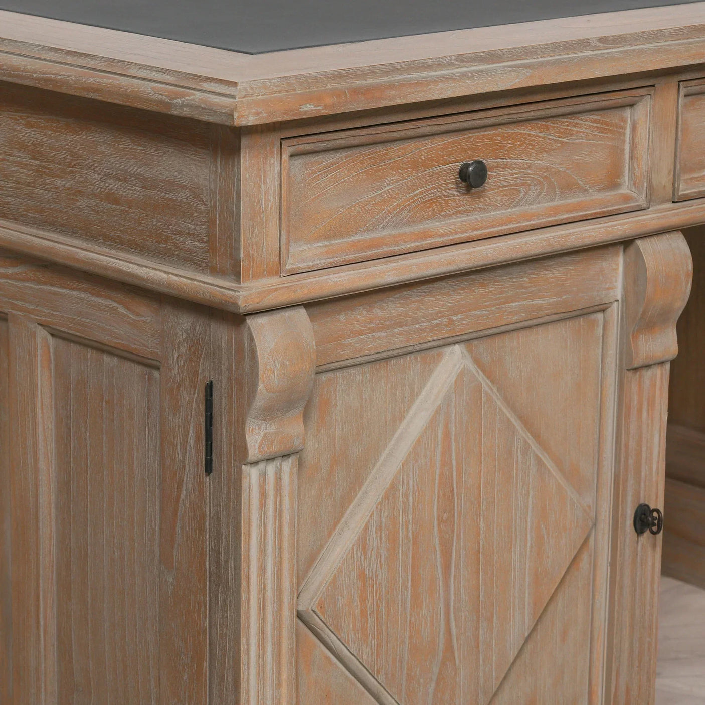Rustic wood desk corner with carved detailing, drawer and cupboard door features visible