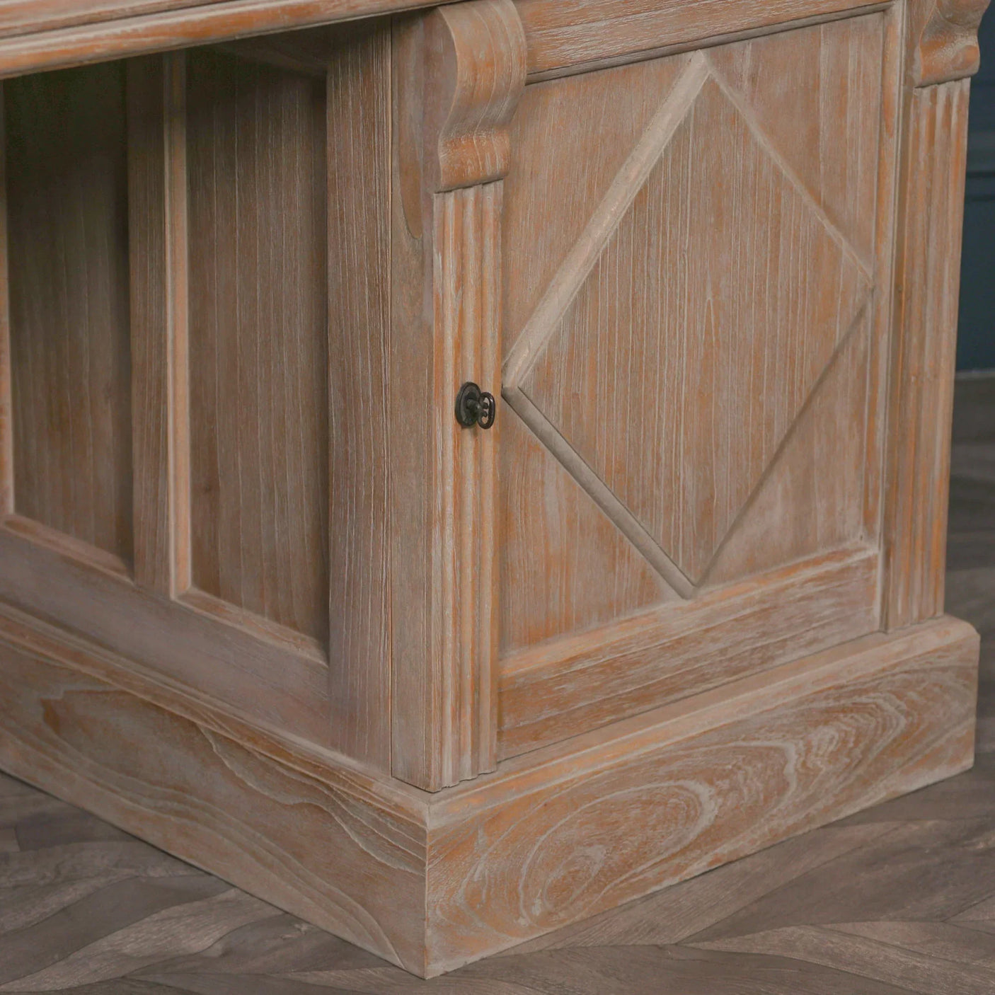 Rustic wooden sideboard corner with paneled detail and diamond design on cabinet door