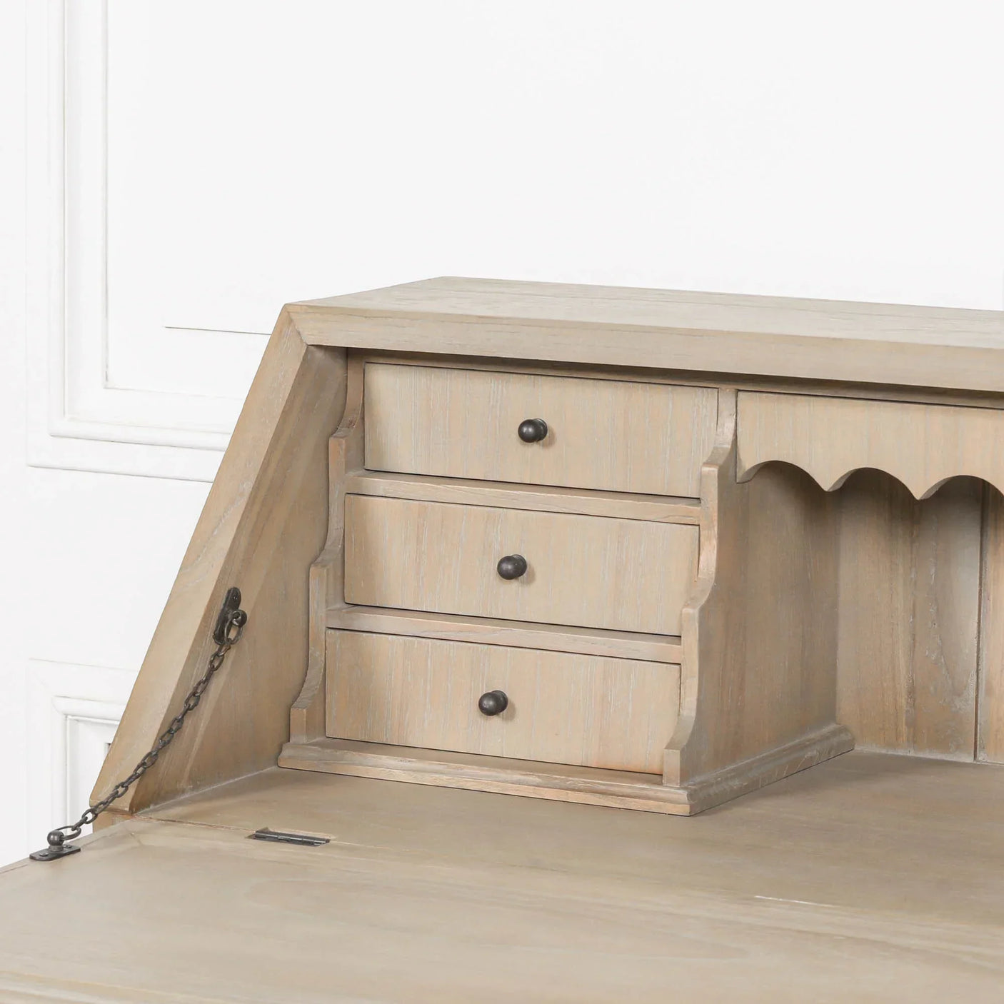 Light wood desk with three small drawers and metal handles, close-up of storage area