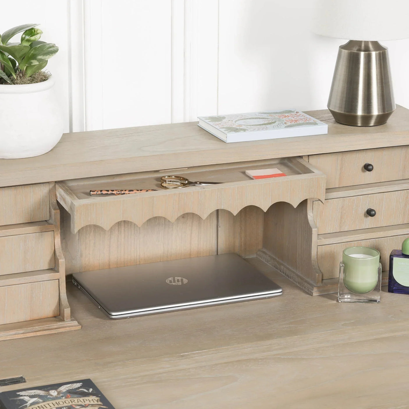 Wooden desk organiser with storage drawers, scalloped trim, and laptop underneath