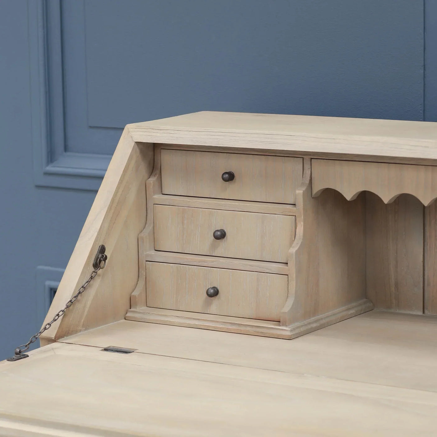 Light wood desk close-up showing three small drawers and scalloped shelf detail
