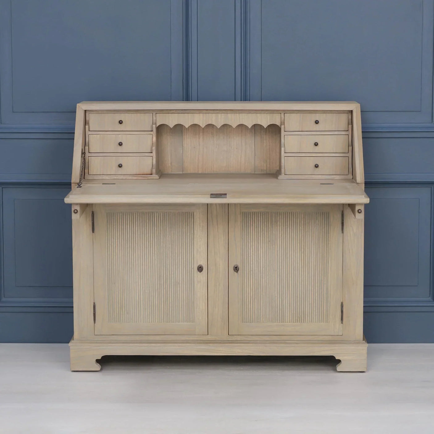 Light oak writing desk with drop-down surface, six small drawers, and double door cabinet base
