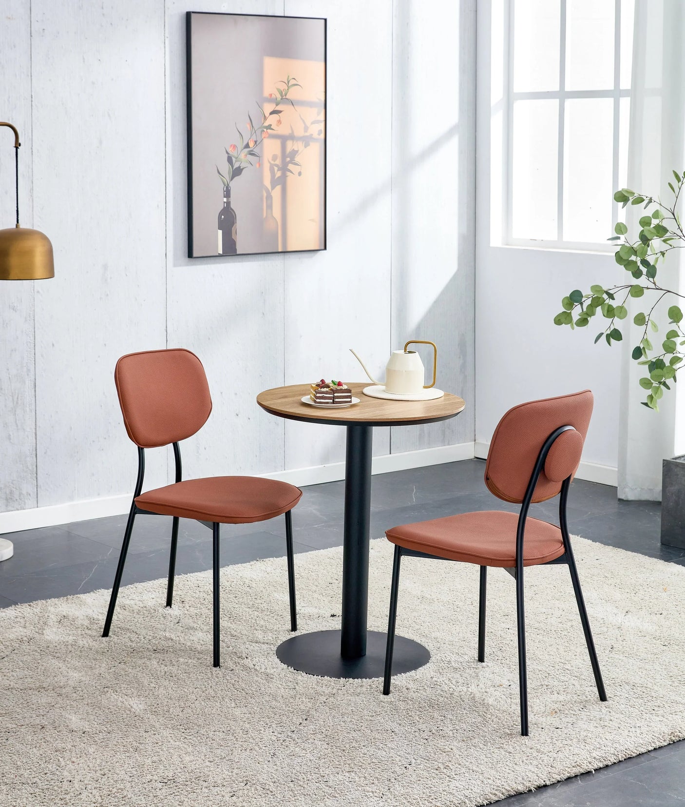 Round oak dining table with black pedestal base and two salmon chairs on cream rug