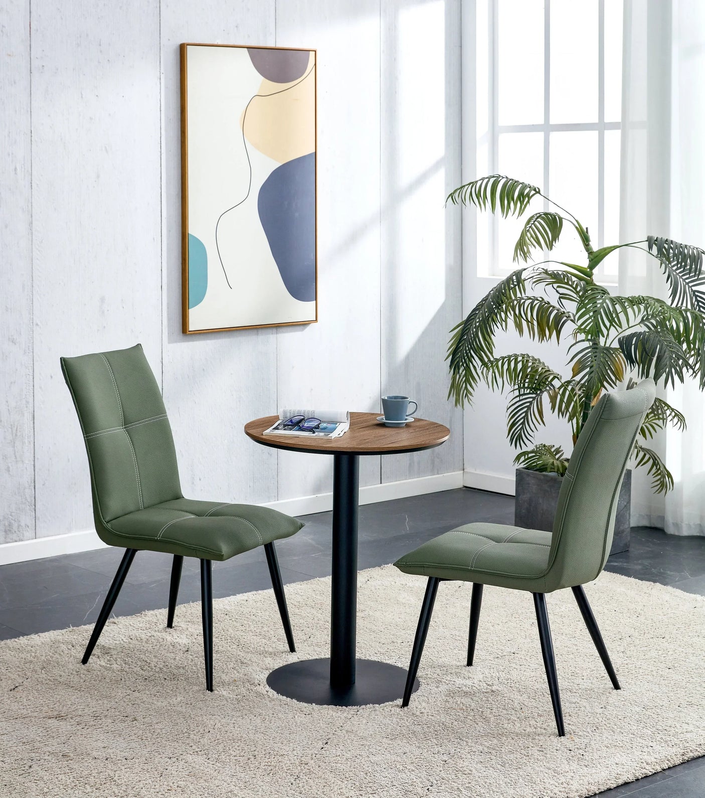 Round walnut dining table with two green chairs in modern room