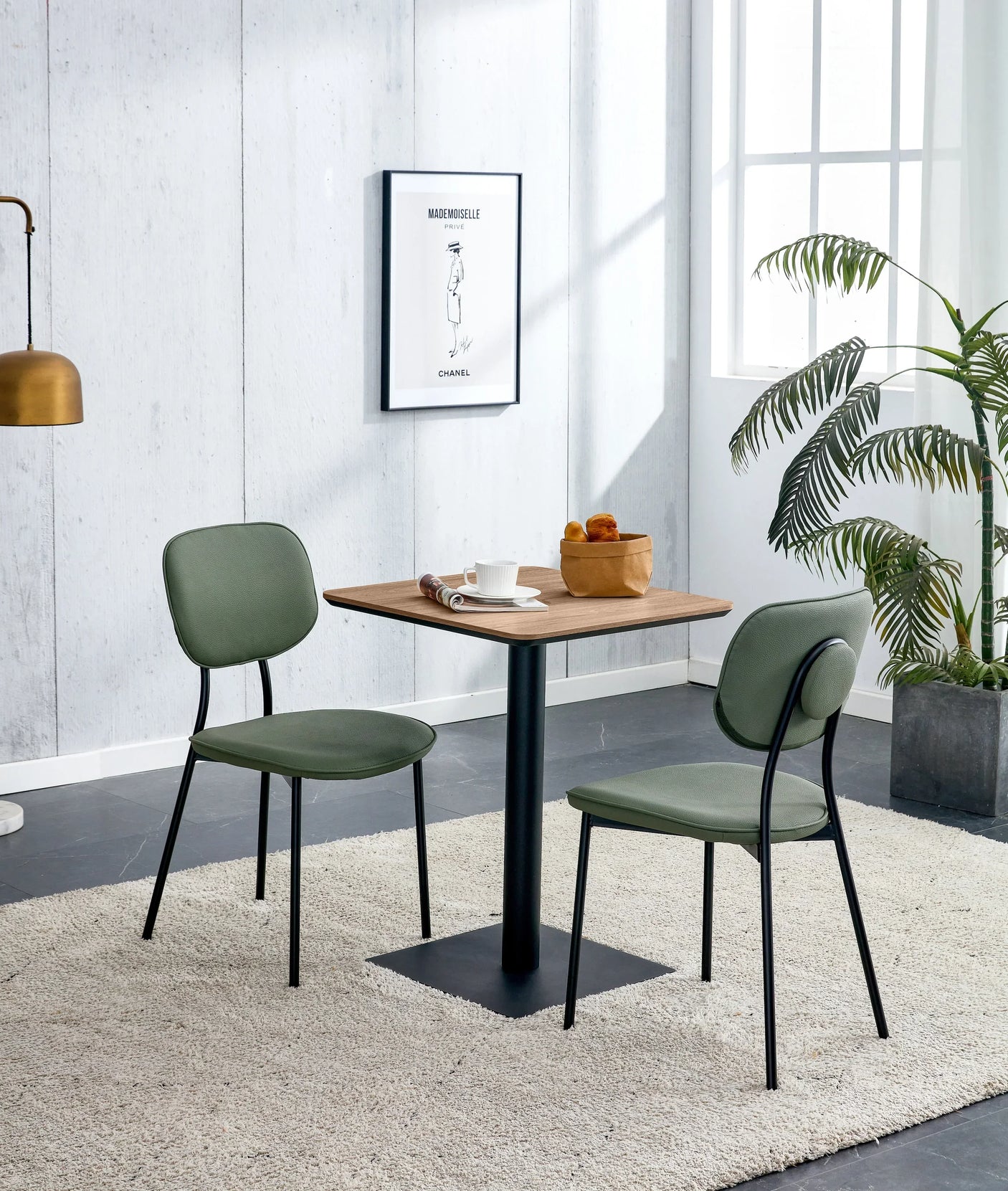 Square walnut dining table with two Capri green chairs in modern dining room setting