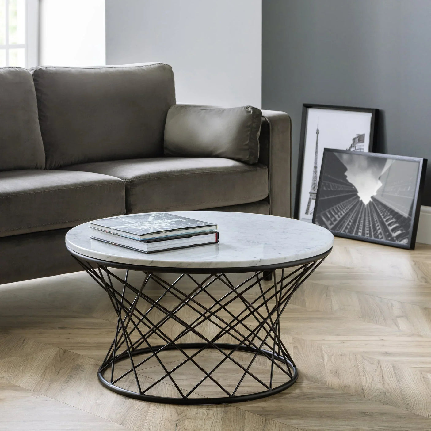 Round marble coffee table with black metal base in living room setting next to grey sofa