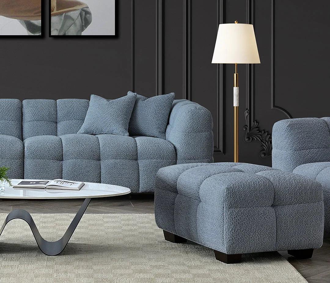 Grey boucle sofa and ottoman set with cushions next to marble coffee table in modern living room