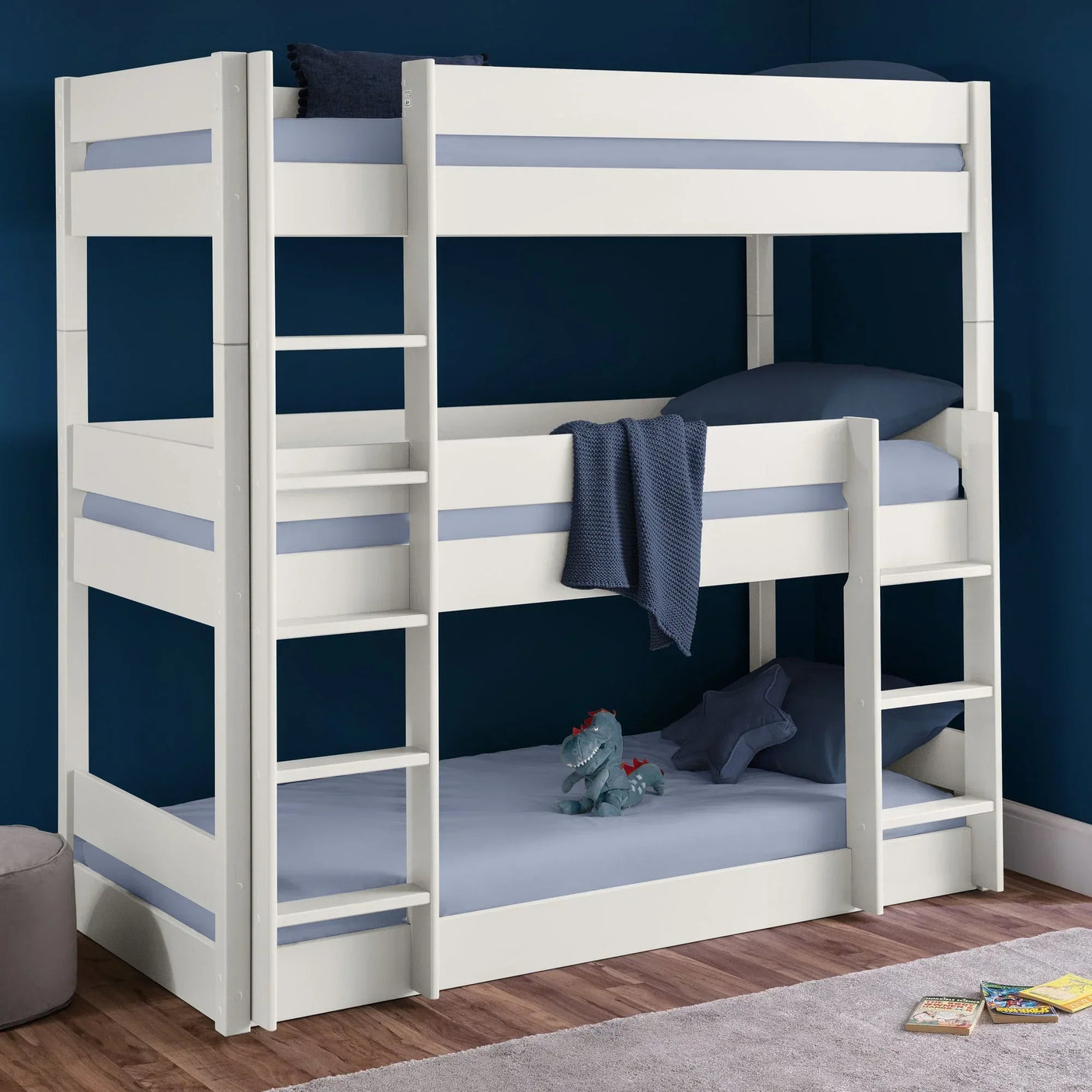 White triple bunk bed with ladders, blue bedding, and plush toy in a modern kids room