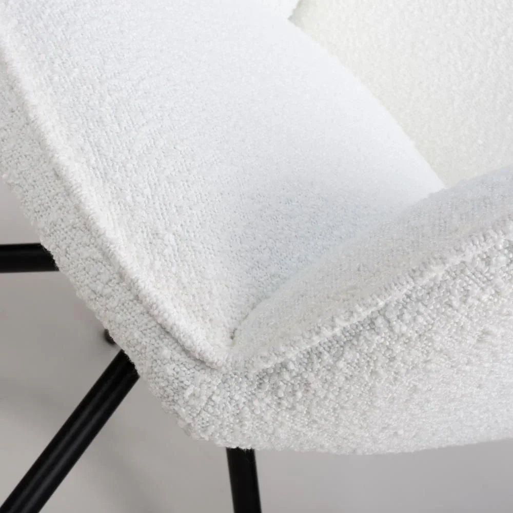 Close-up of white boucle upholstered dining chair with black metal legs