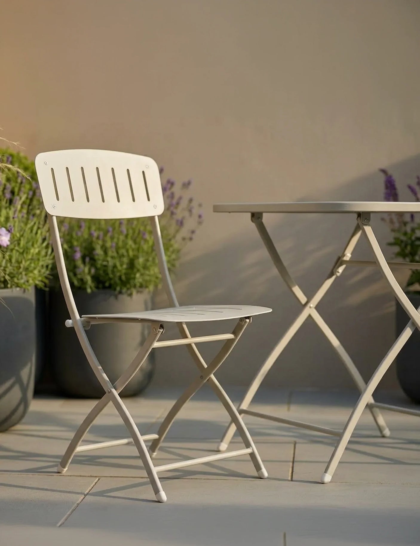 Cream metal folding patio chair and table set on tiled outdoor terrace