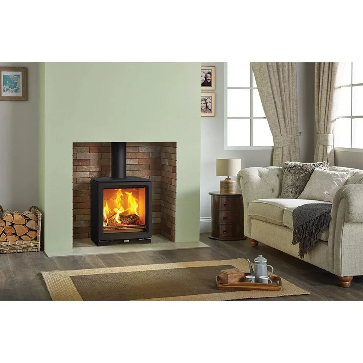 Modern wood burning stove in brick fireplace with beige sofa and tray on coffee table