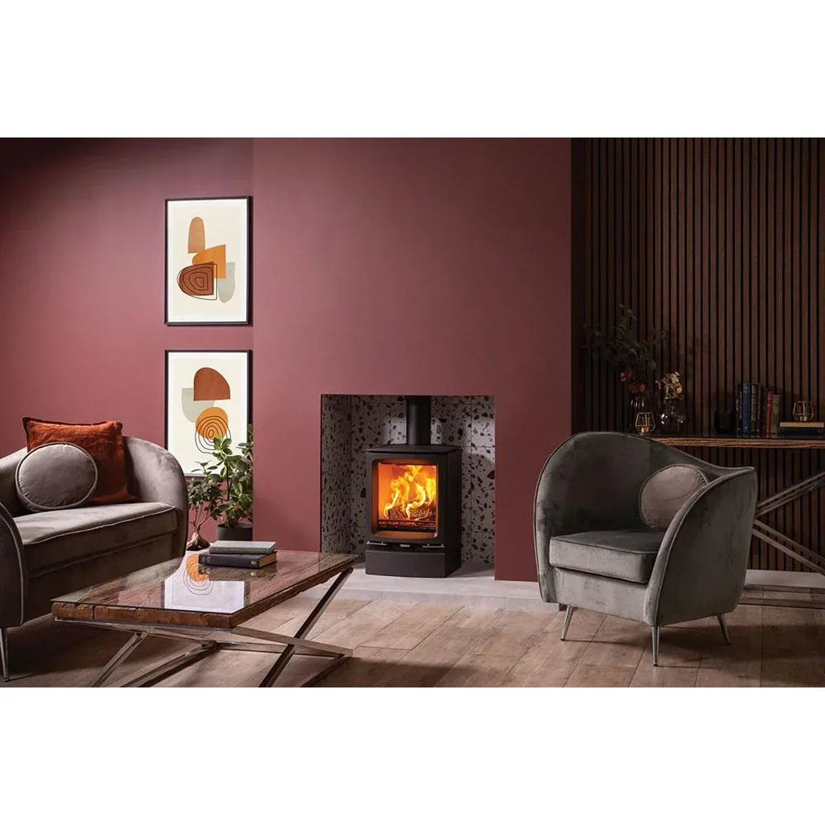 Modern living room with velvet armchair, wood burning stove, and glass coffee table