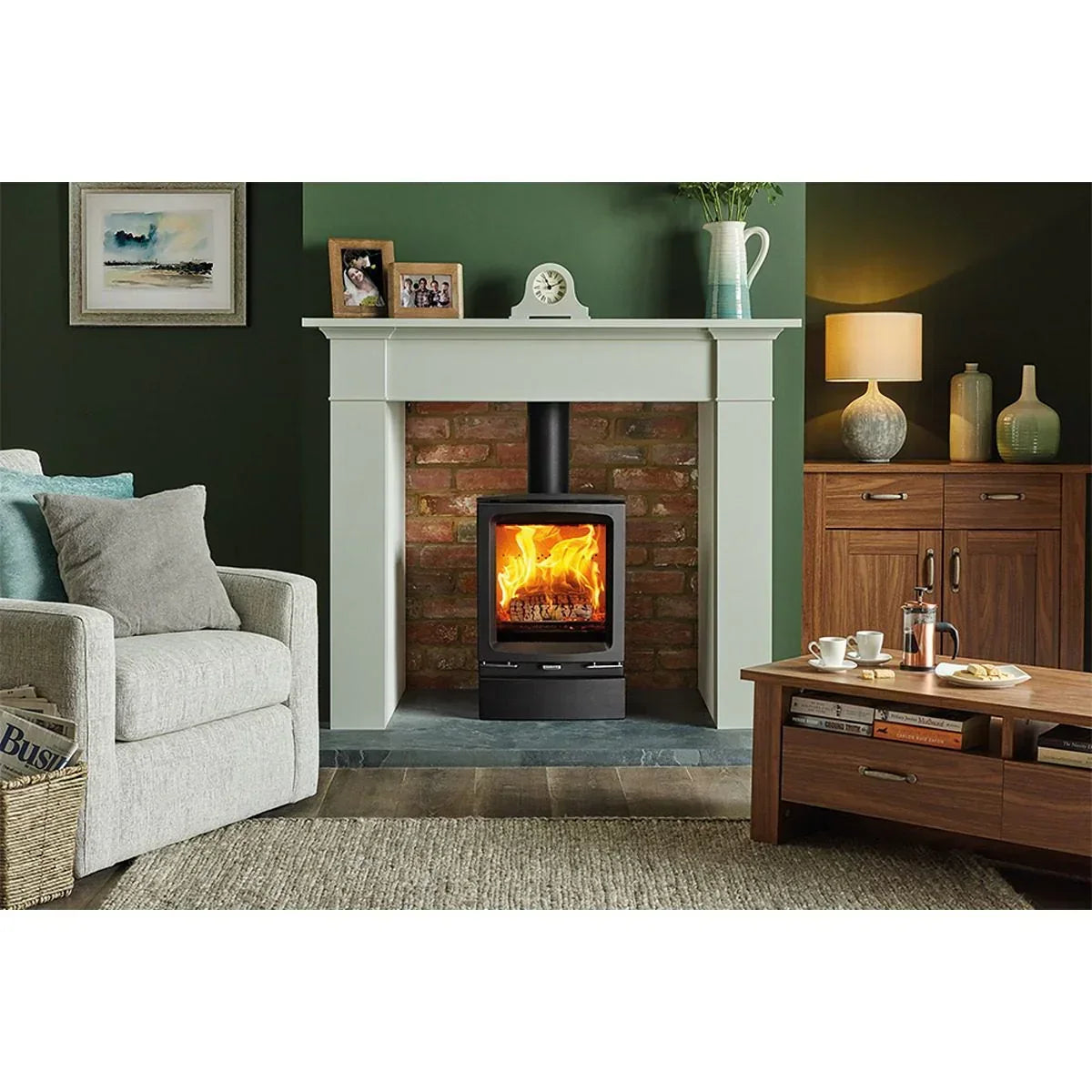 Modern wood burning stove with glass door in brick fireplace, cozy living room setting