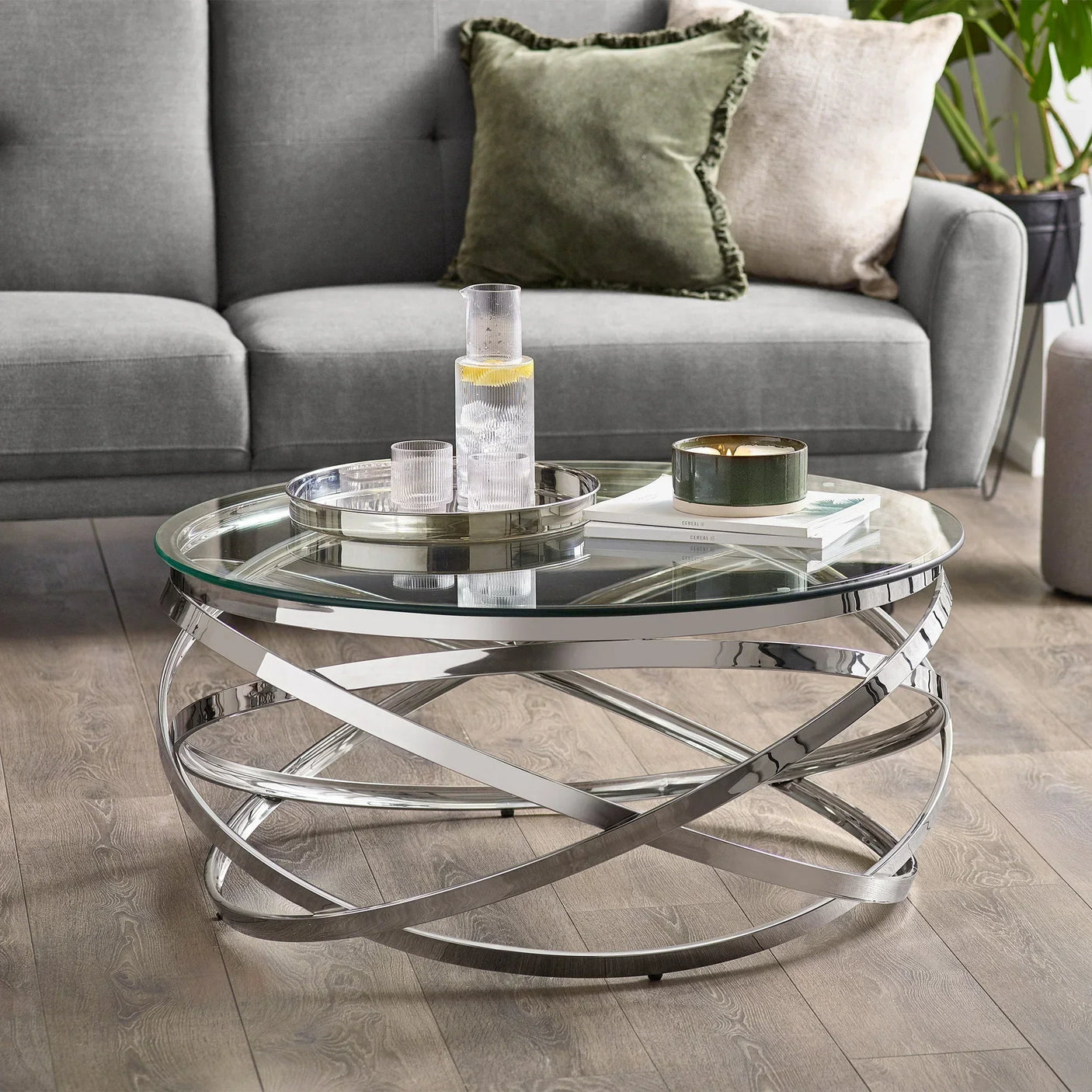 Glass top coffee table with chrome metal base in modern living room setting