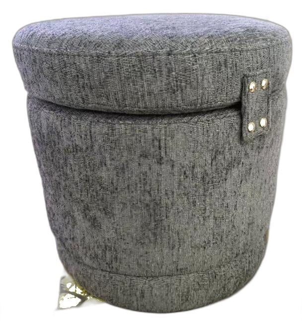 A round, upholstered storage ottoman or stool with a textured gray fabric cover, featuring a small side tab with gold-tone metal studs and a small gold tag near the base, shown on a plain white background.