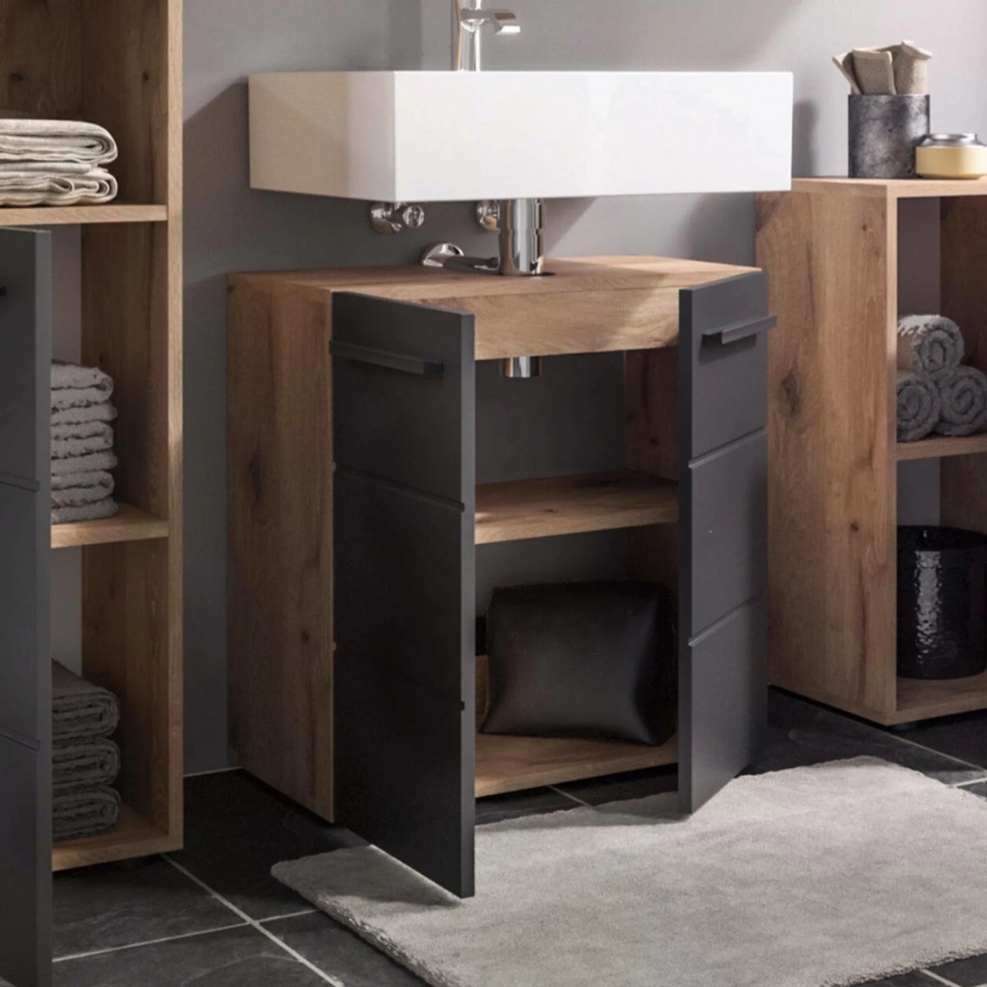 Oak bathroom vanity unit with black doors and open shelving below white basin sink