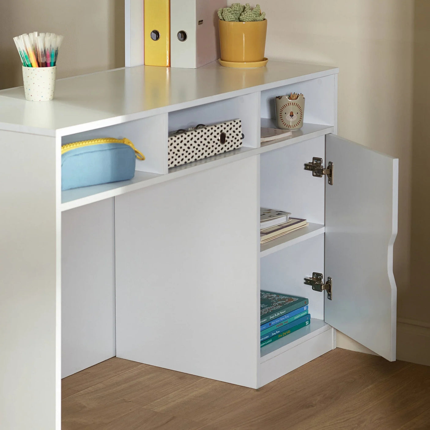 White desk with open storage cubbies and cupboard, featuring books, files, and accessories
