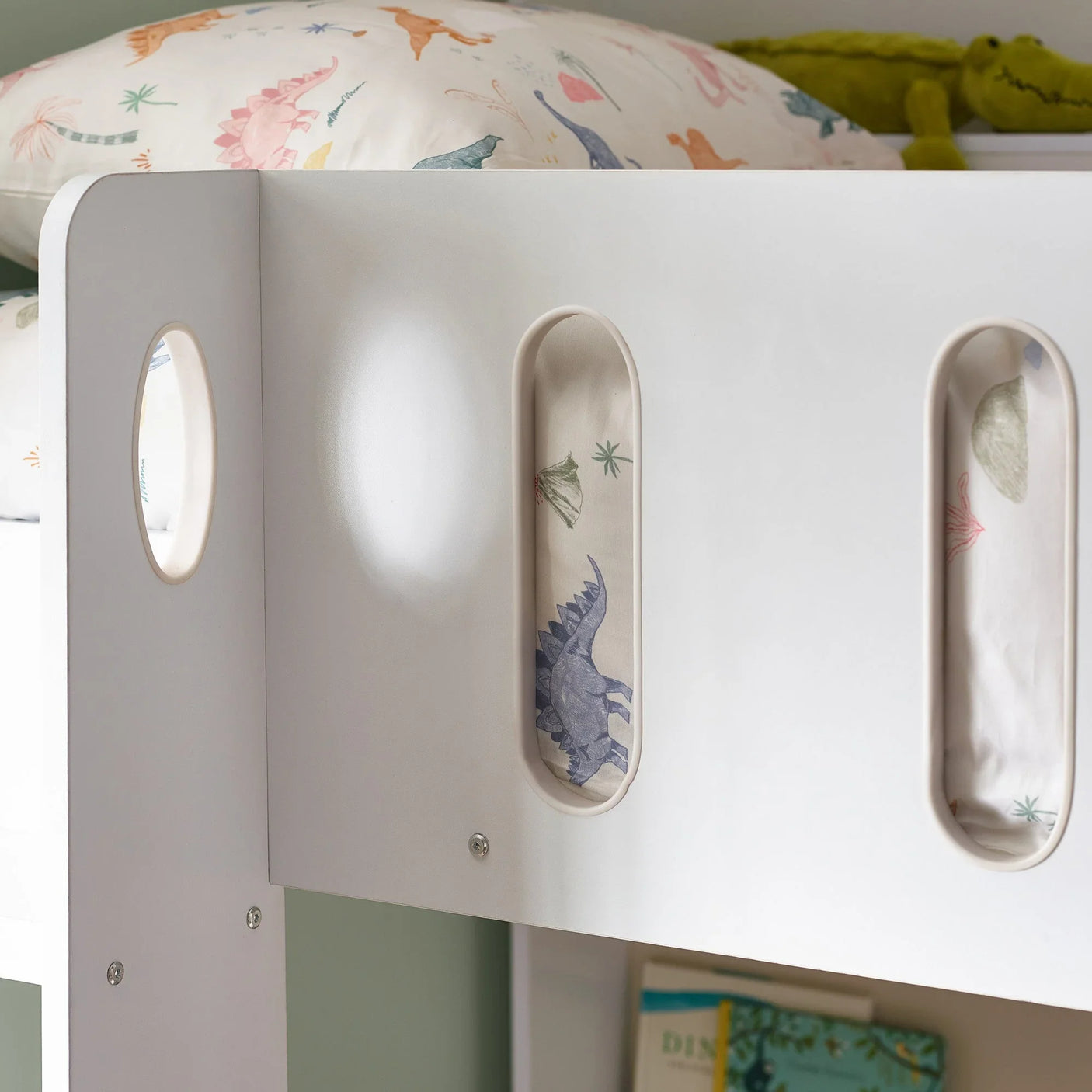 White kids wooden bunk bed with dinosaur bedding and oval safety rail cut-outs