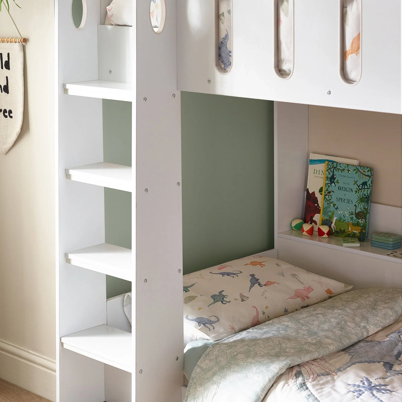 White bunk bed with built-in shelves and dinosaur print bedding in a child’s room