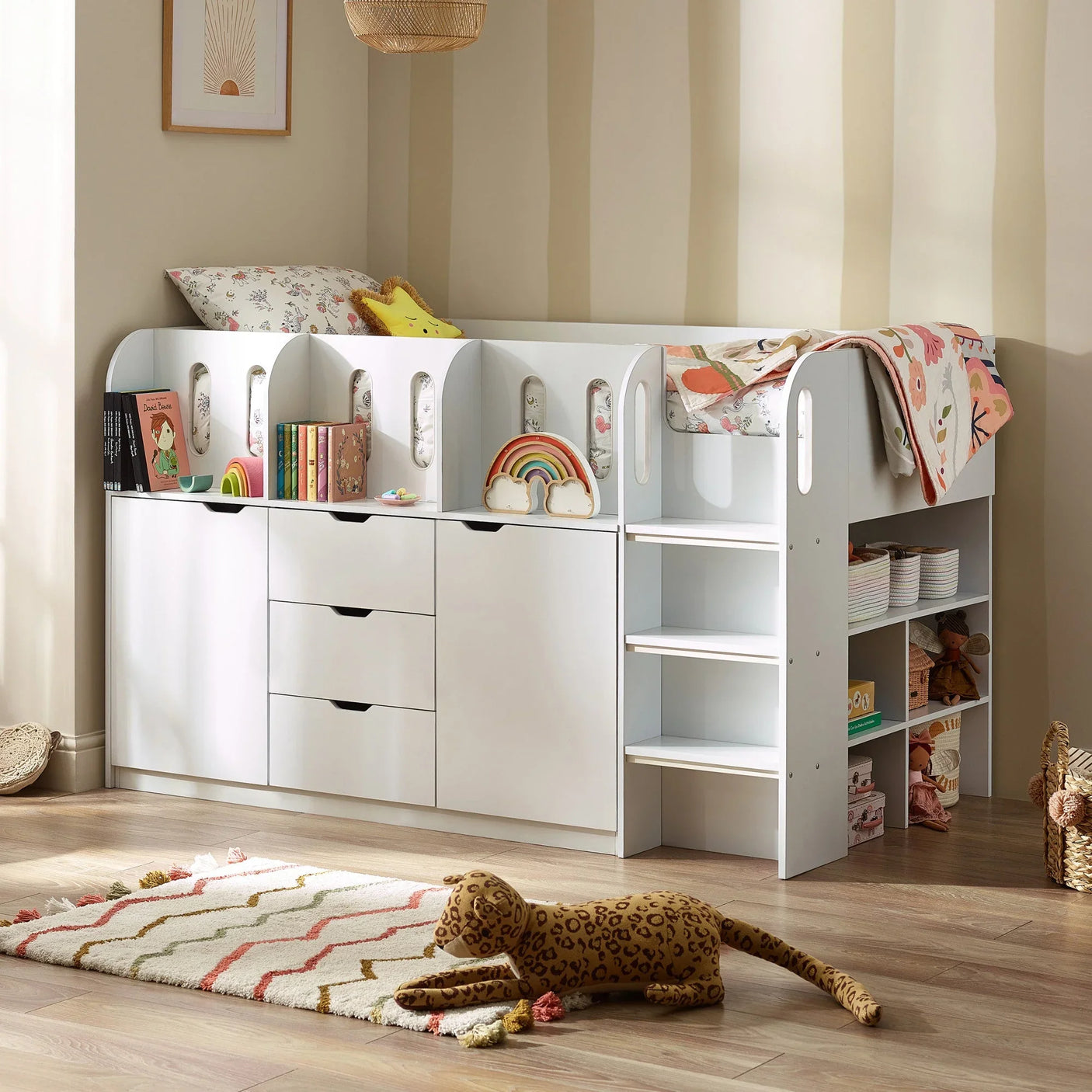 White kids cabin bed with storage drawers, shelves, steps and pastel bedding in a playroom