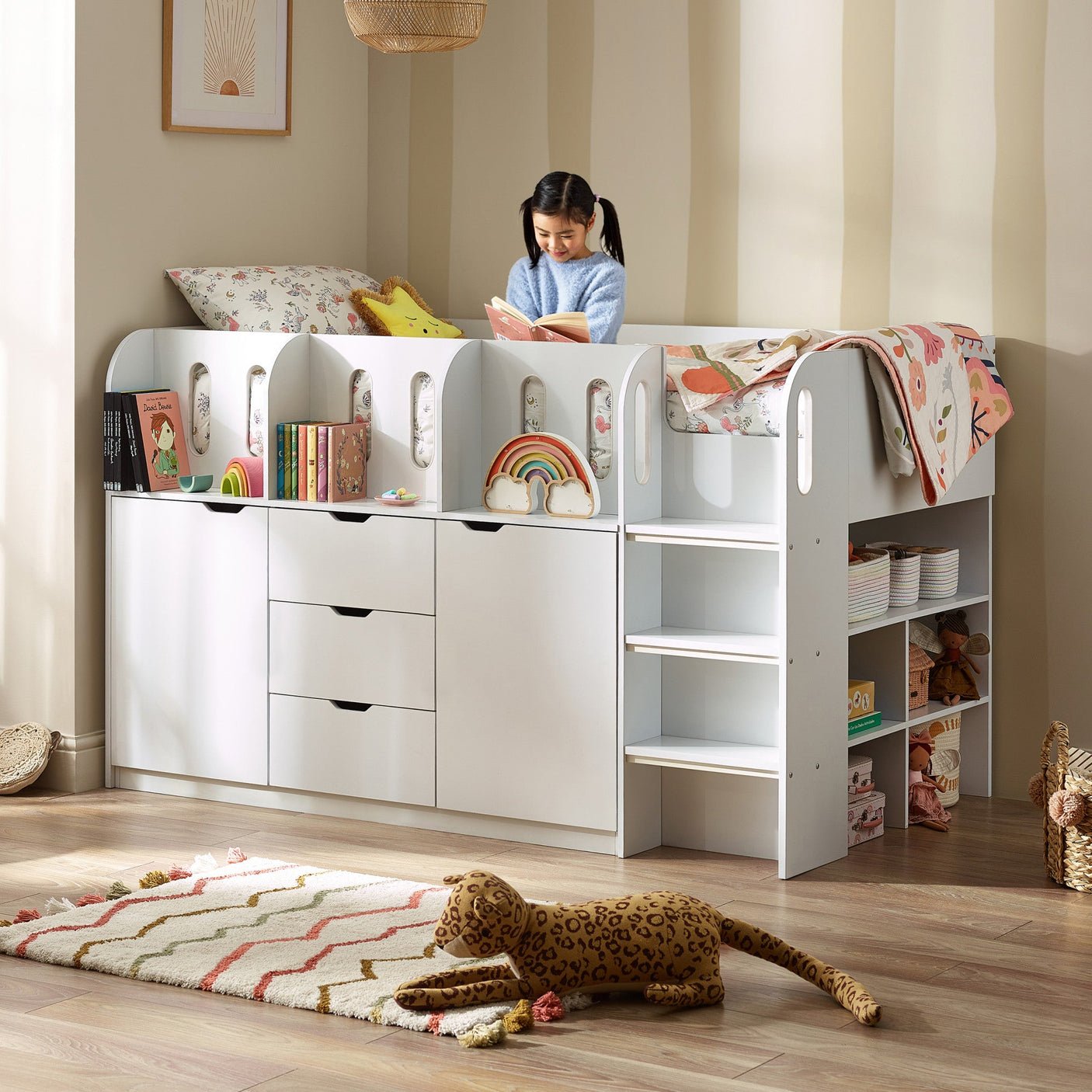 White mid-sleeper bed with under-bed storage and shelving, child reading on top