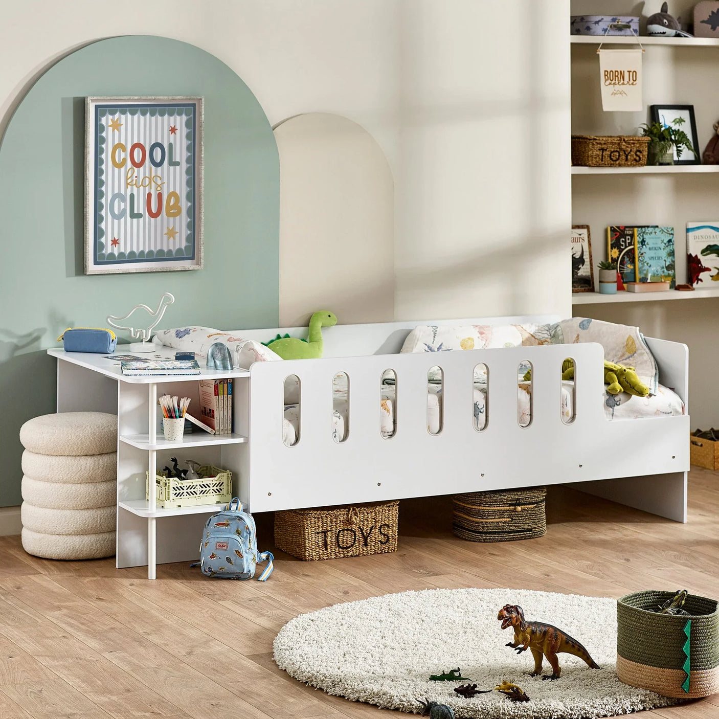White kids bed with side safety rail, built-in storage shelves, and dinosaur toys in playroom