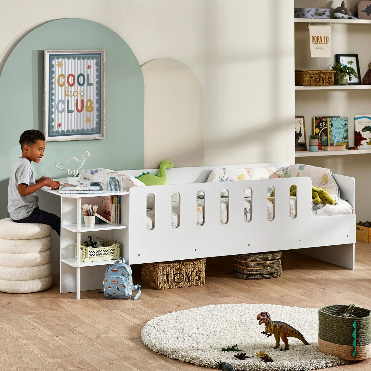 White kids bed with side rail, integrated desk, and toy storage in modern bedroom