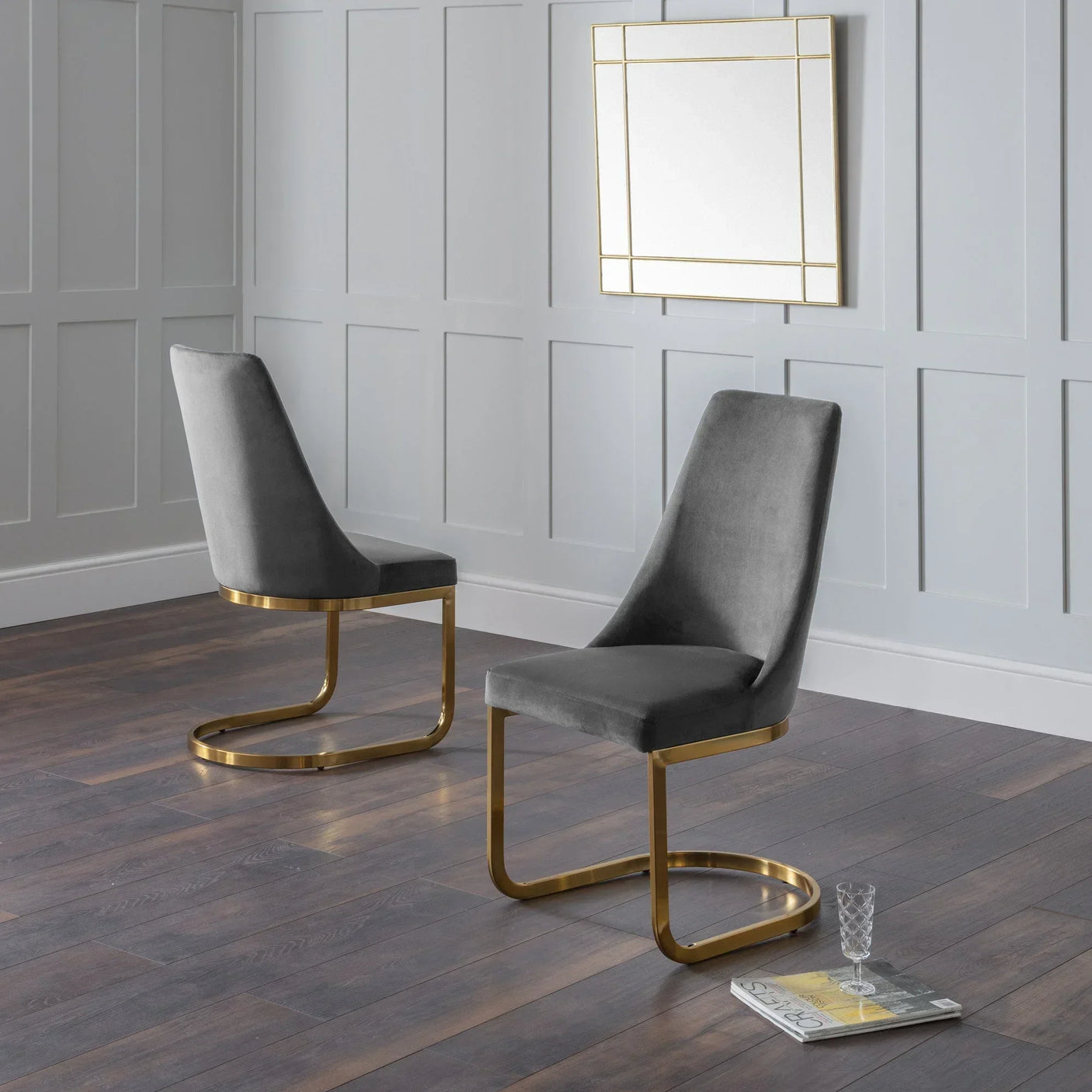Pair of grey velvet dining chairs with gold cantilever legs on wooden floor