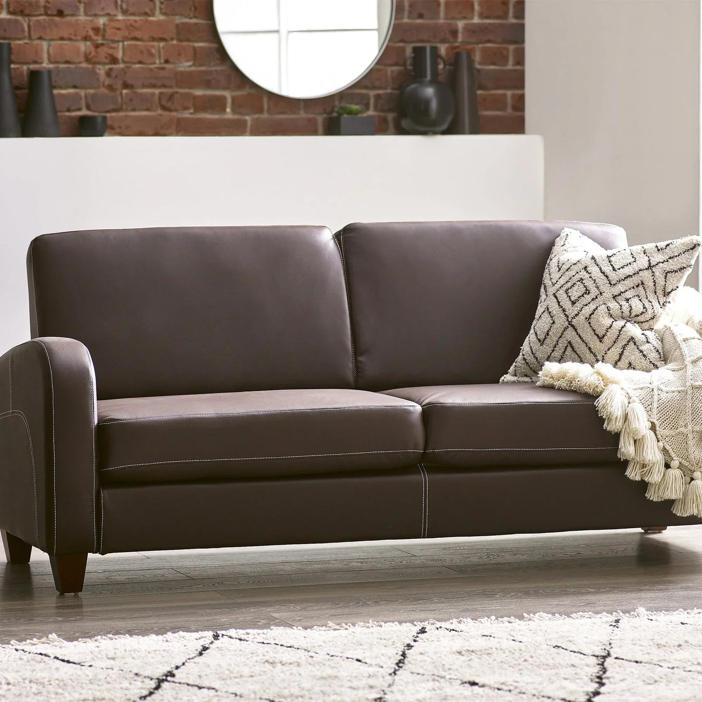 Chestnut three seater sofa with patterned cushion and throw in modern living room