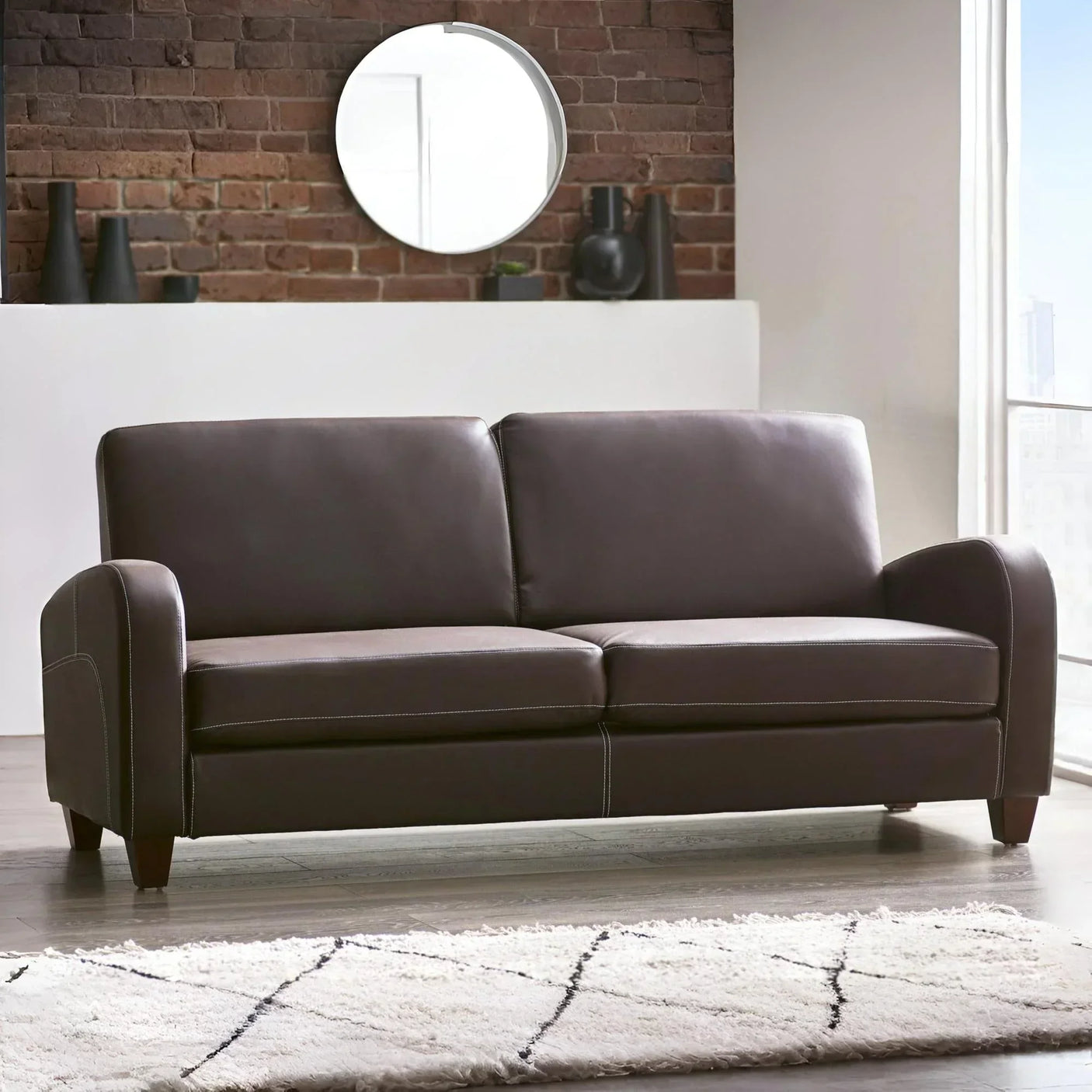 Brown leather 3 seater sofa with wooden legs in modern living room with brick accent wall