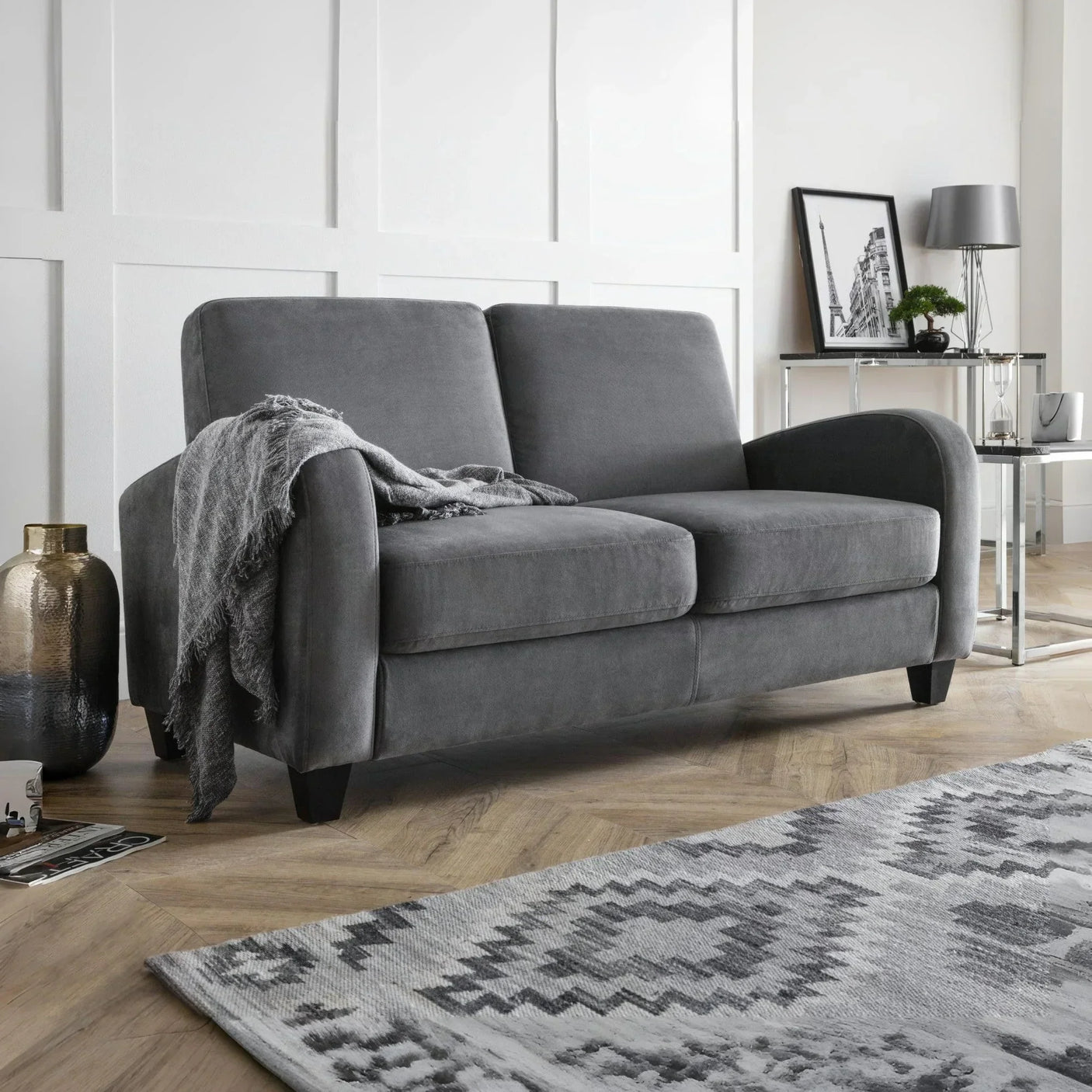 Grey fabric sofa with two seat cushions, throw blanket, wooden legs, in a modern living room