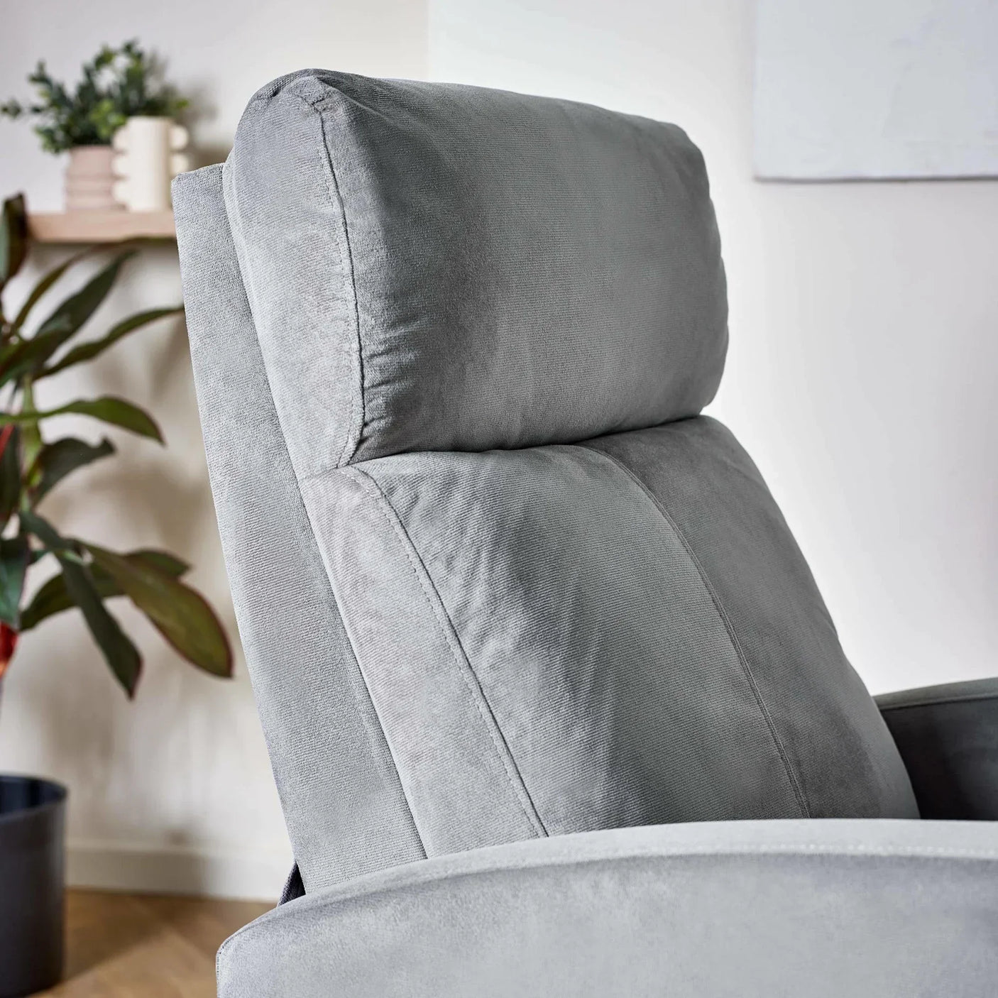 Light grey fabric recliner chair with padded backrest in a modern living room setting