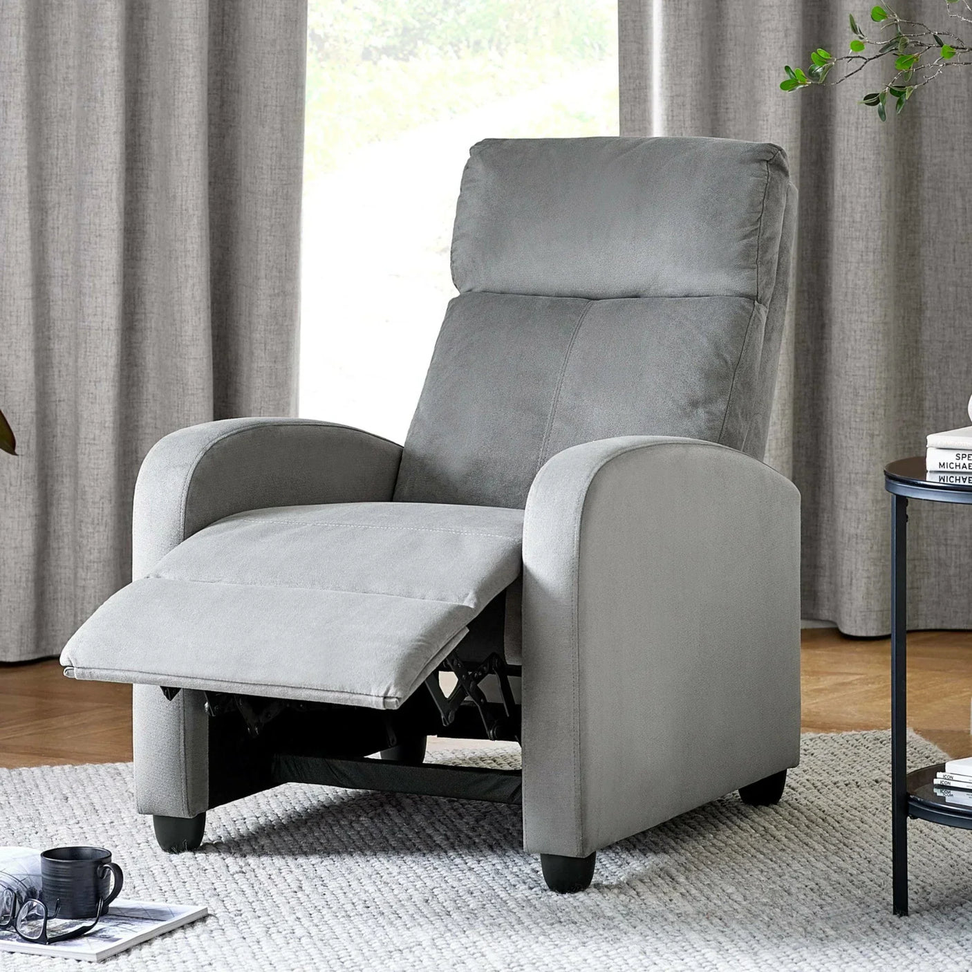 Grey fabric recliner chair with footrest extended in living room with neutral decor