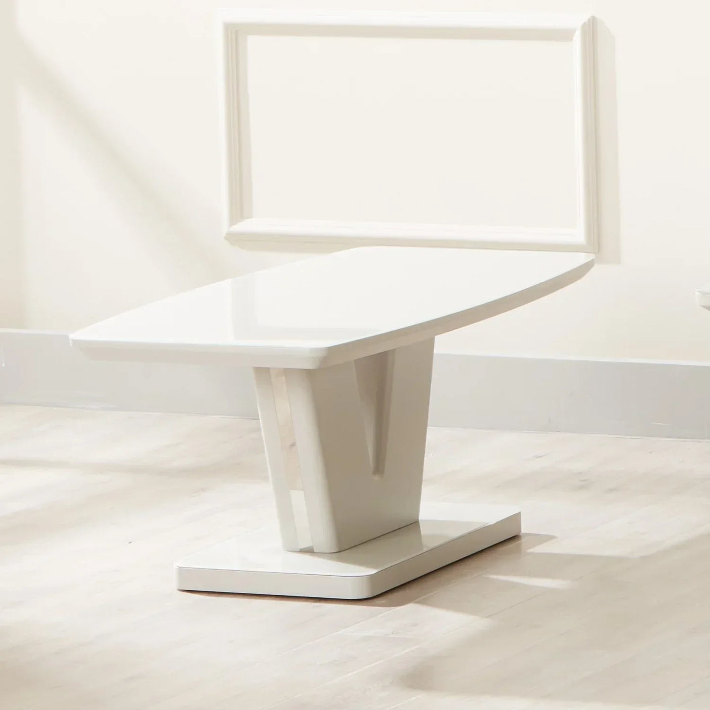 White gloss coffee table with modern angular base on light wood floor