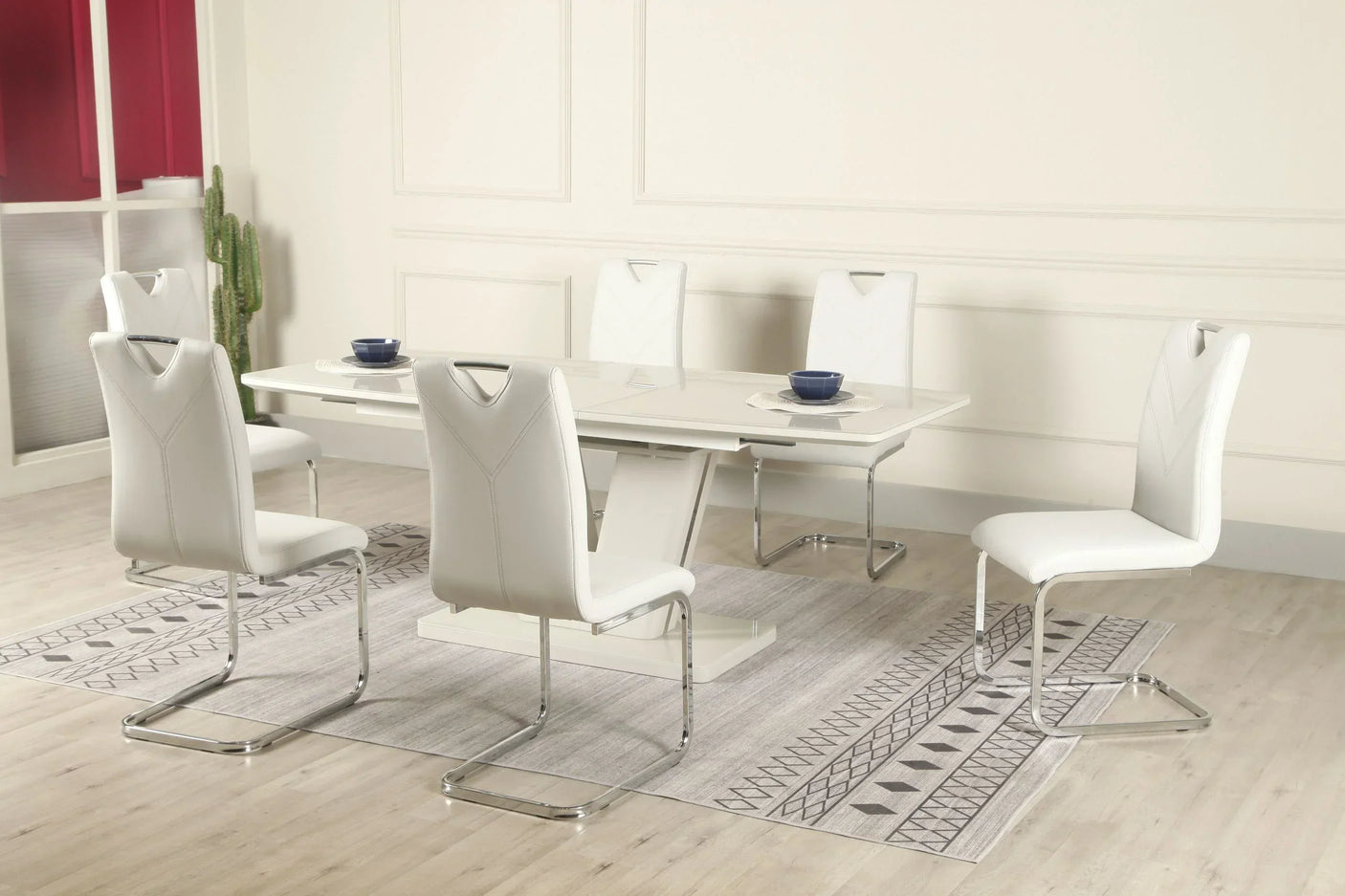 Glossy white extension dining table with six white leather chairs on patterned grey rug