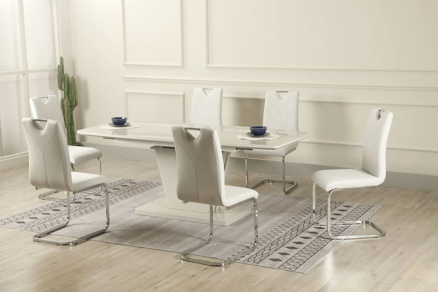 White extension dining table with six chrome leg chairs on a patterned rug in modern room