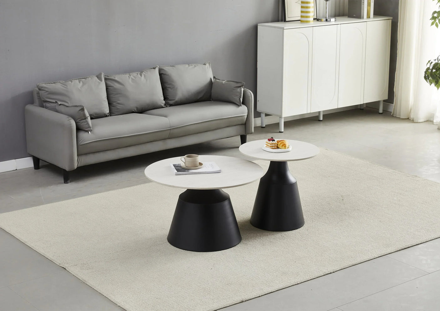 Modern coffee table and lamp table with round white tops and black bases in minimalist living room