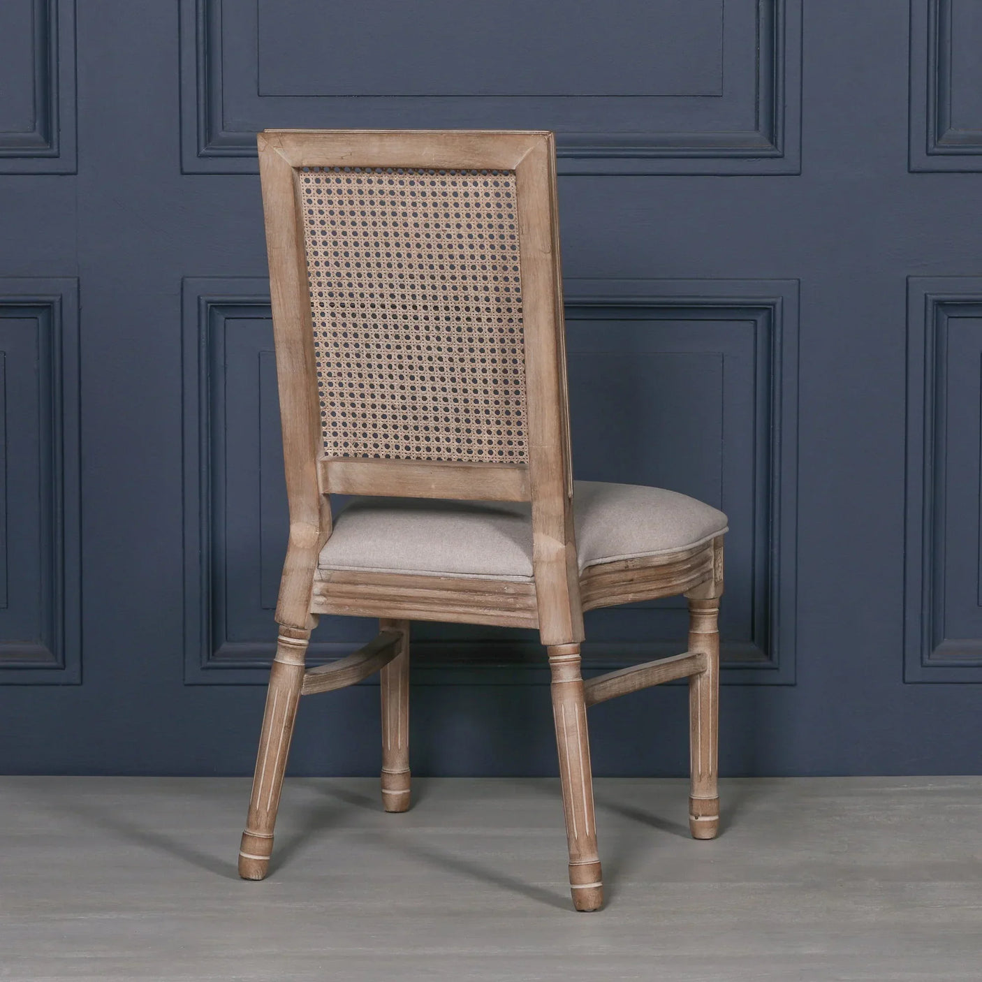 Oak dining chair with rattan backrest and cushioned seat, shown from the rear