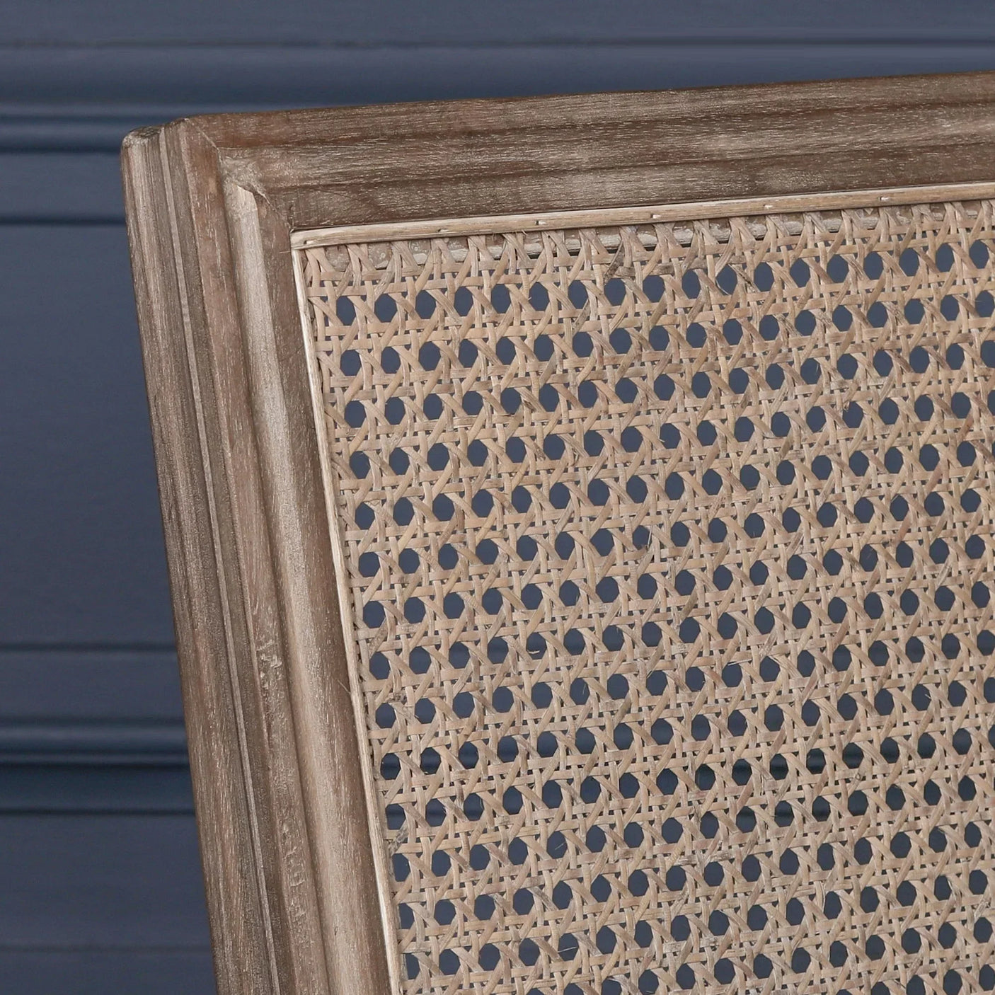 Close-up of cane dining chair backrest with light wood frame and woven rattan detail