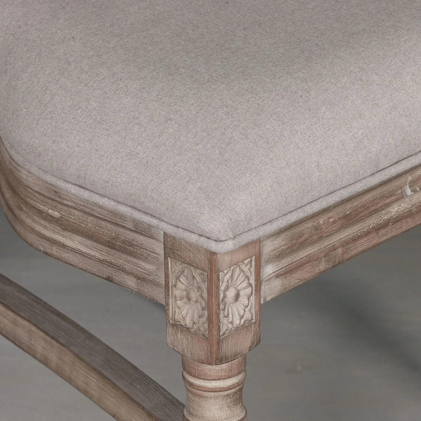Grey upholstered dining chair seat with carved wood frame and floral corner detail