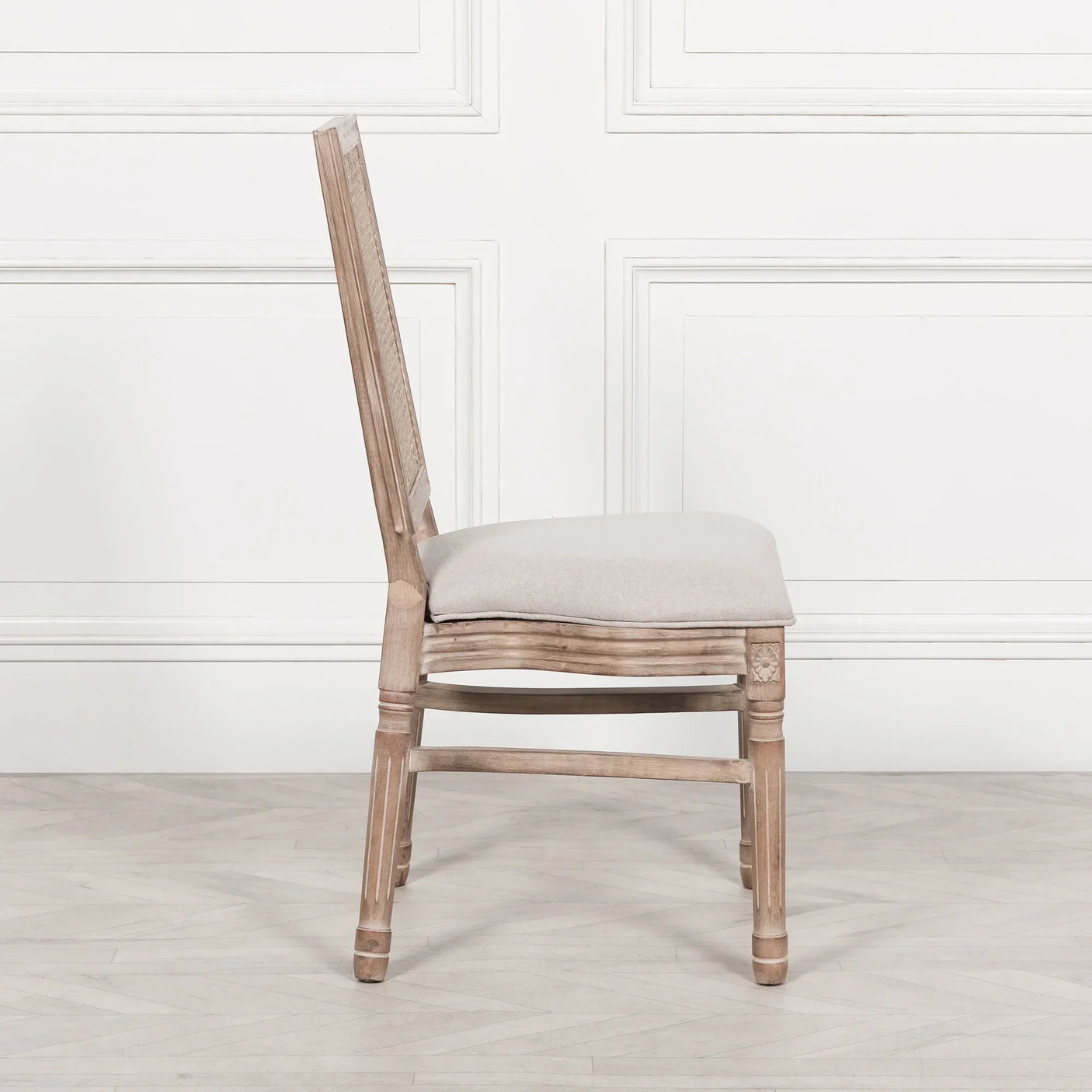 Side view of wooden dining chair with cushioned seat and carved details
