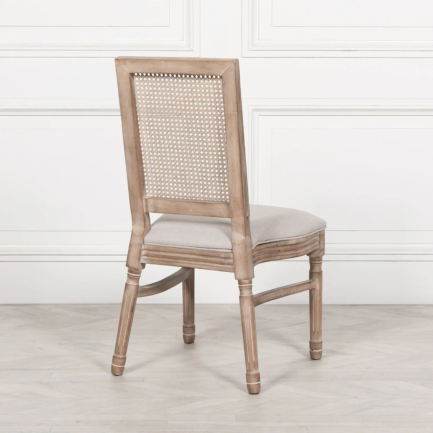 Natural wood dining chair with cane back and light fabric seat, rear view