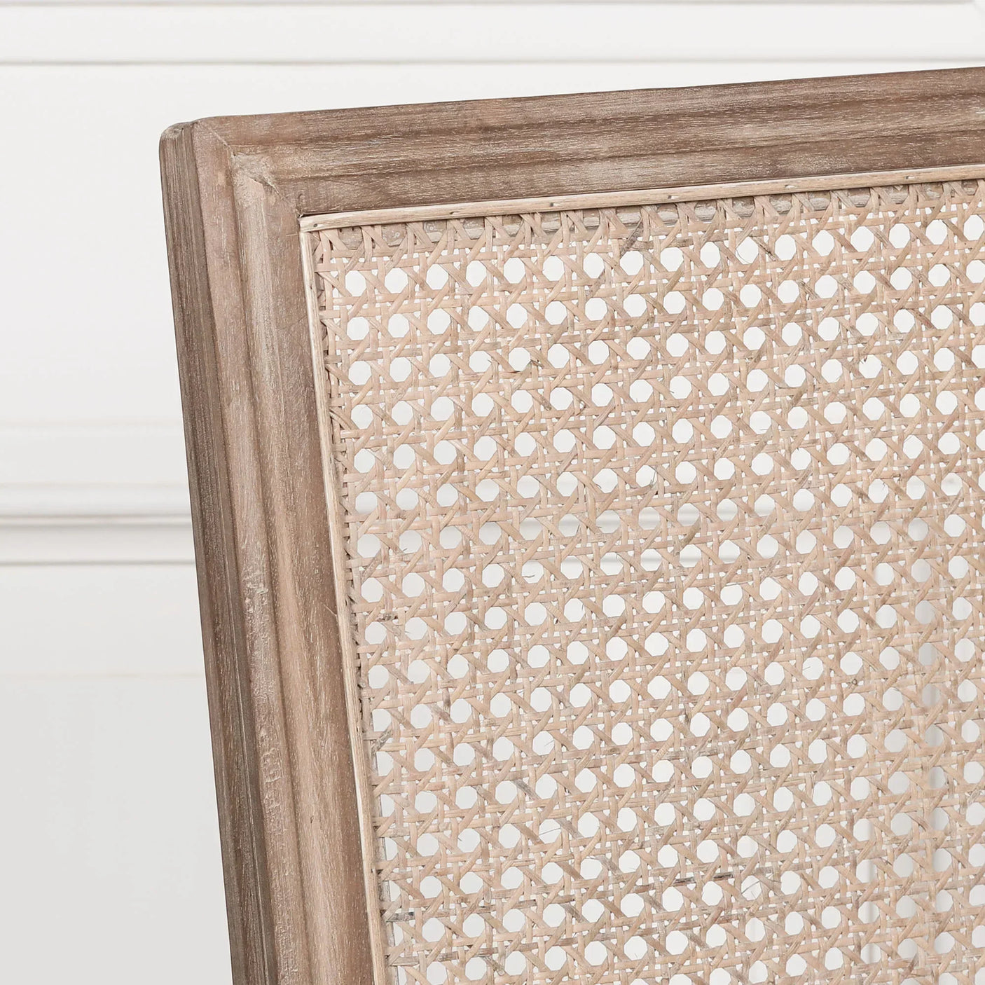 Close view of natural rattan dining chair back with light wood frame