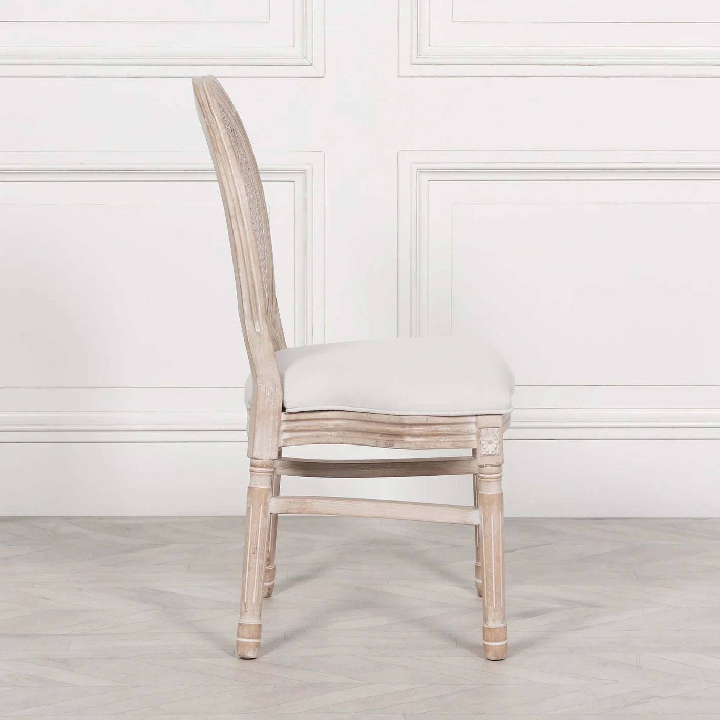Side view of upholstered dining chair with wooden frame and light fabric seat