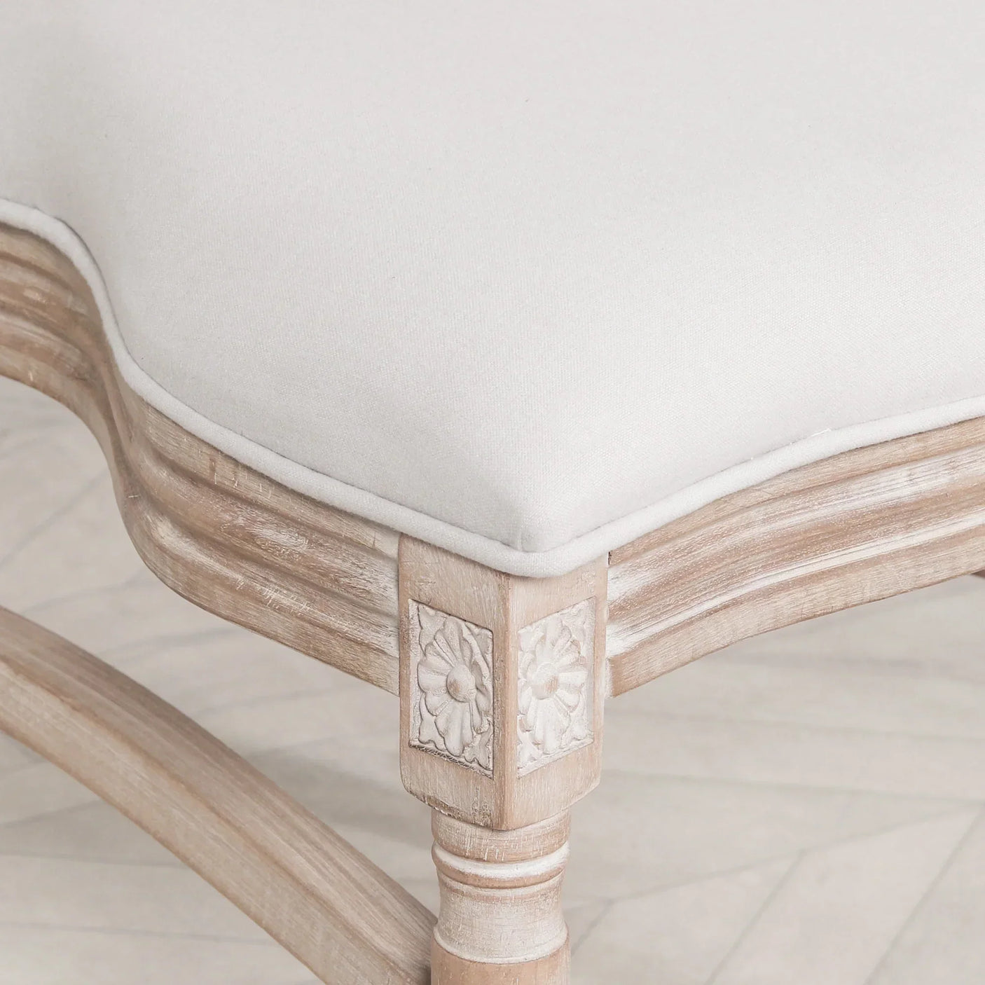 Carved wooden dining bench leg with cream upholstered seat and floral detail