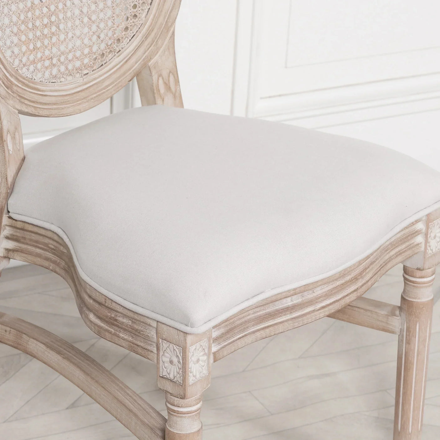 Light oak dining chair with carved floral detail and cream upholstered seat