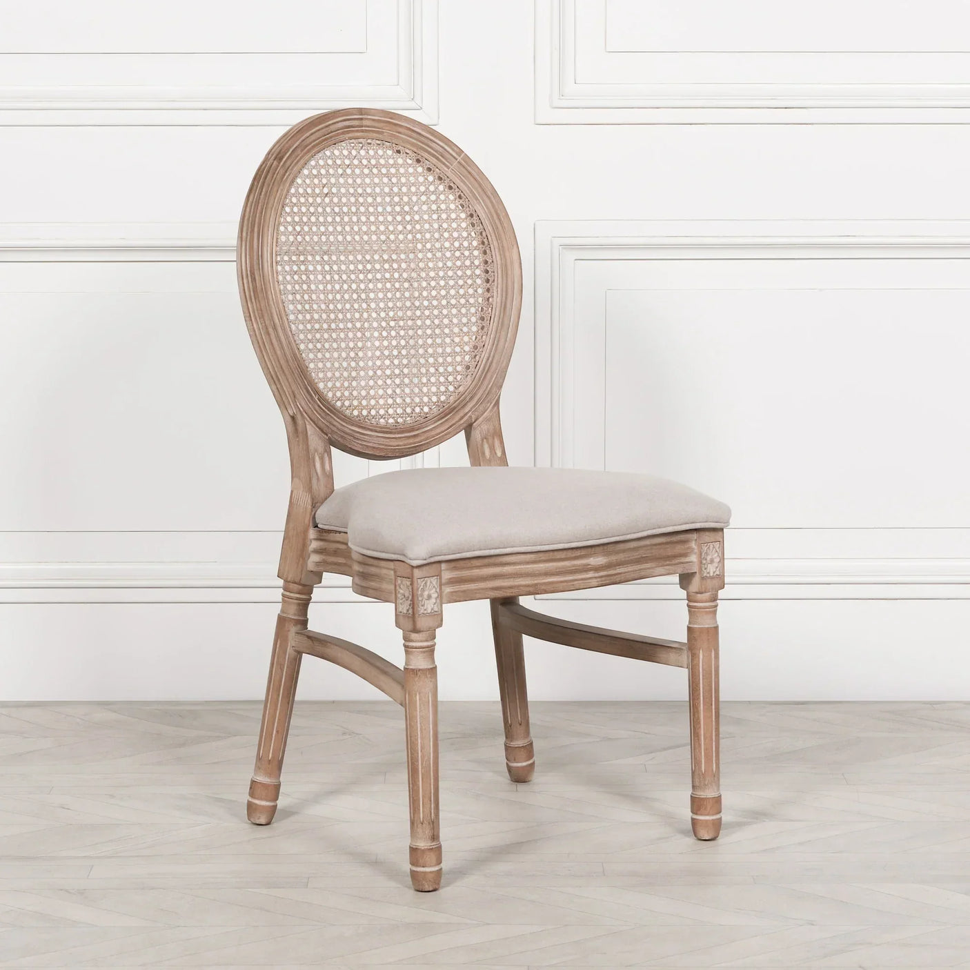 Wooden dining chair with cushioned seat and round rattan backrest against white wall