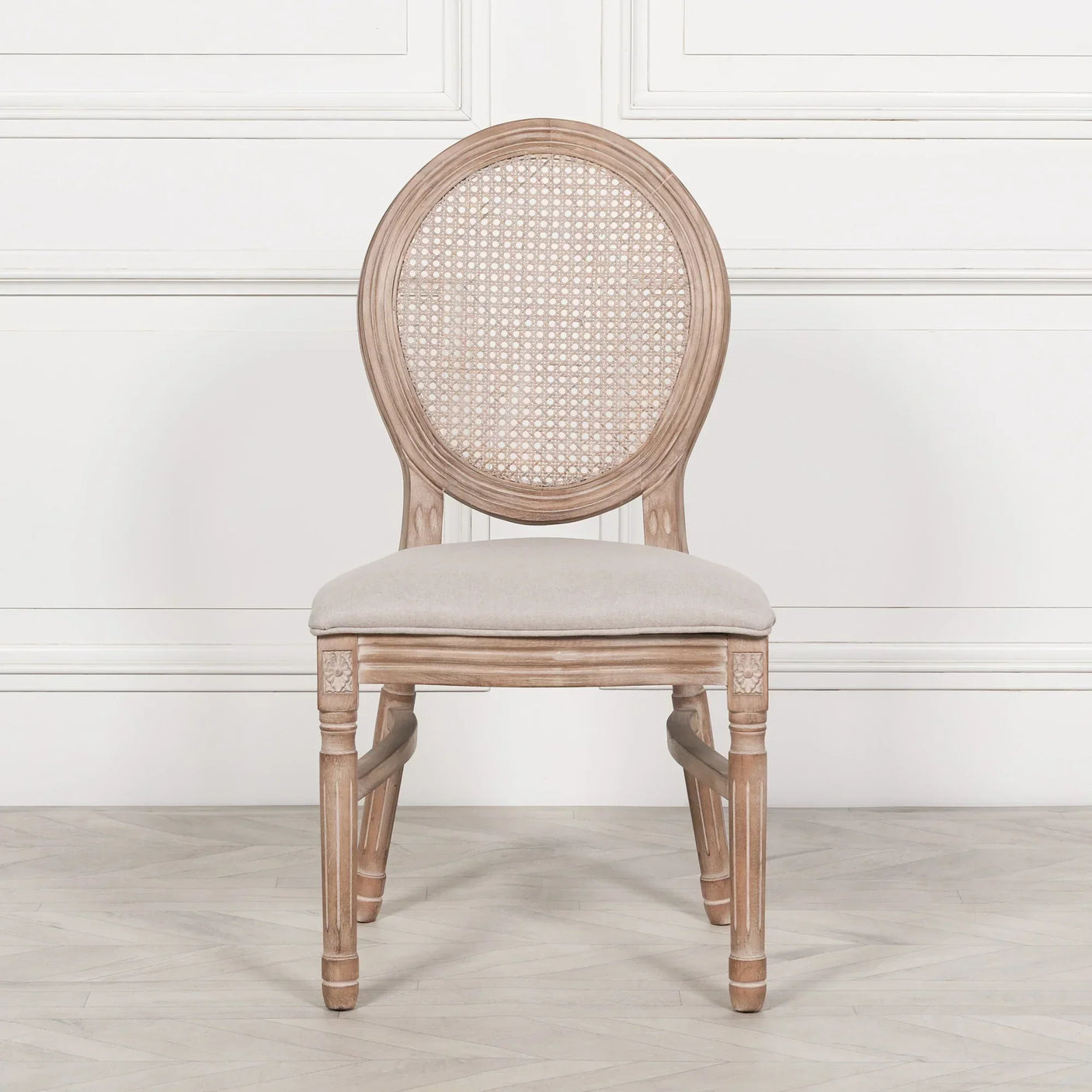 Oak dining chair with round cane back and cream upholstered seat on light wood floor