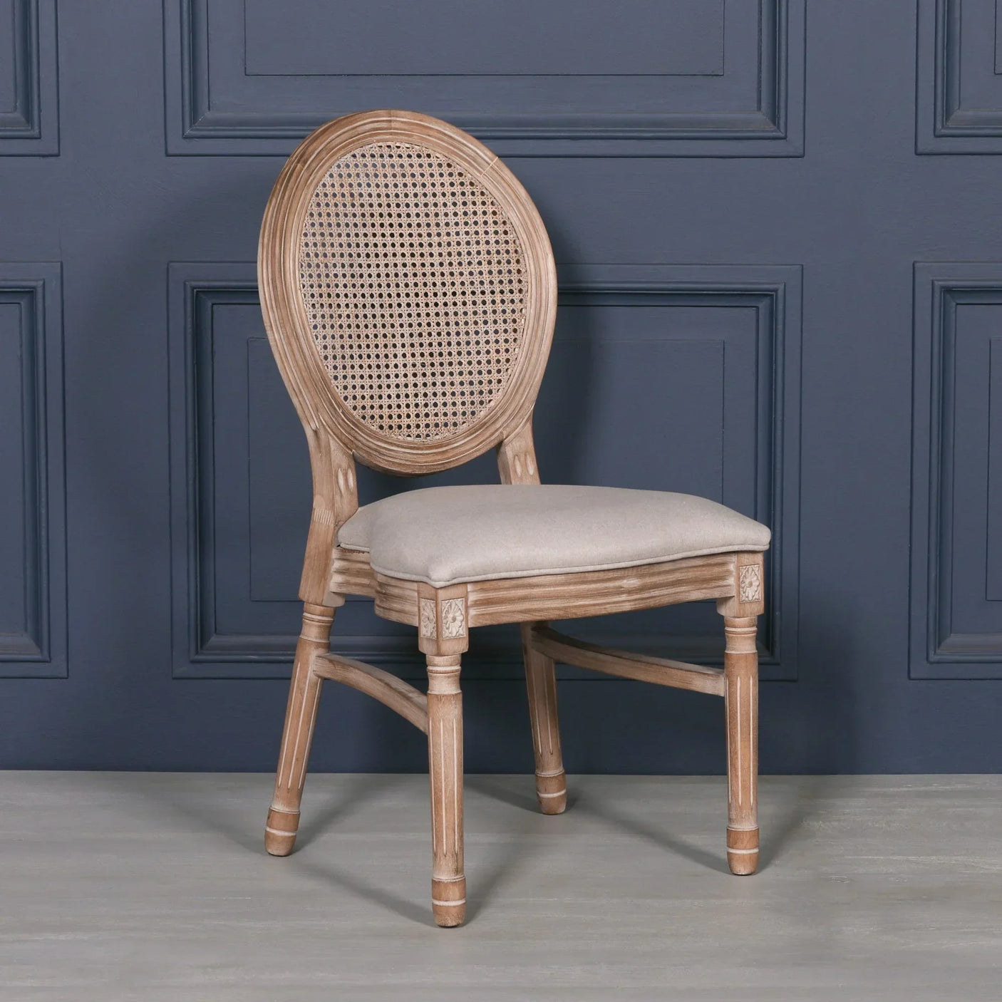 Wooden dining chair with rattan back and padded linen seat against dark panel wall