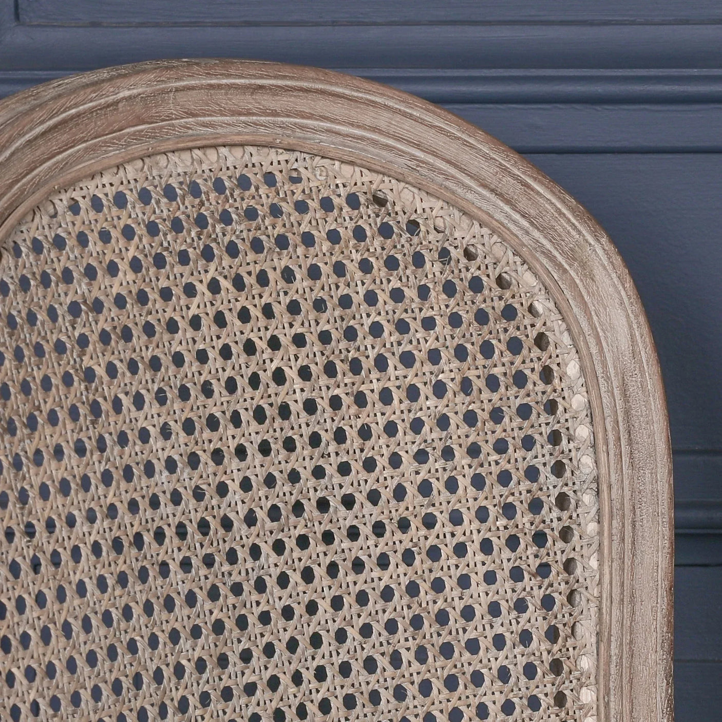 Close-up of cane dining chair backrest with natural wood frame